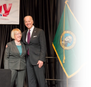 Senator Patty Murray and President Joe Biden smiling together onstage.